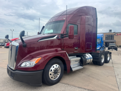 Kenworth T680 tractor in maroon, front-left view, with sleeper cab, dual rear axles, chrome fuel tanks, daytime sky.