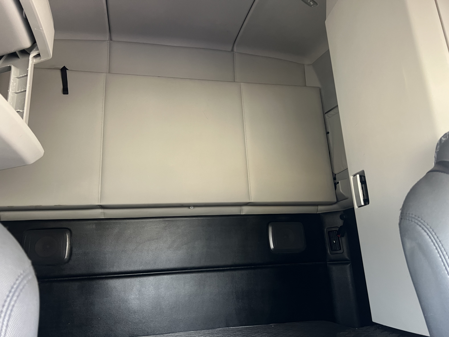 Kenworth T680 cab interior showing storage cabinet with light gray panels and seating in front, overhead sleeper area.
