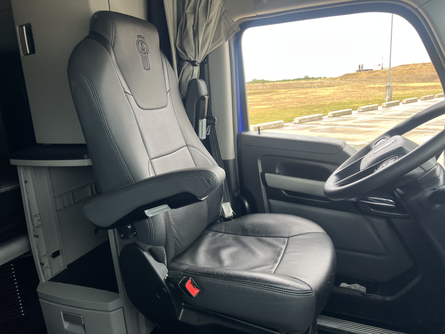 Kenworth T680 cab interior showing driver's seat and steering wheel with badge on seat back