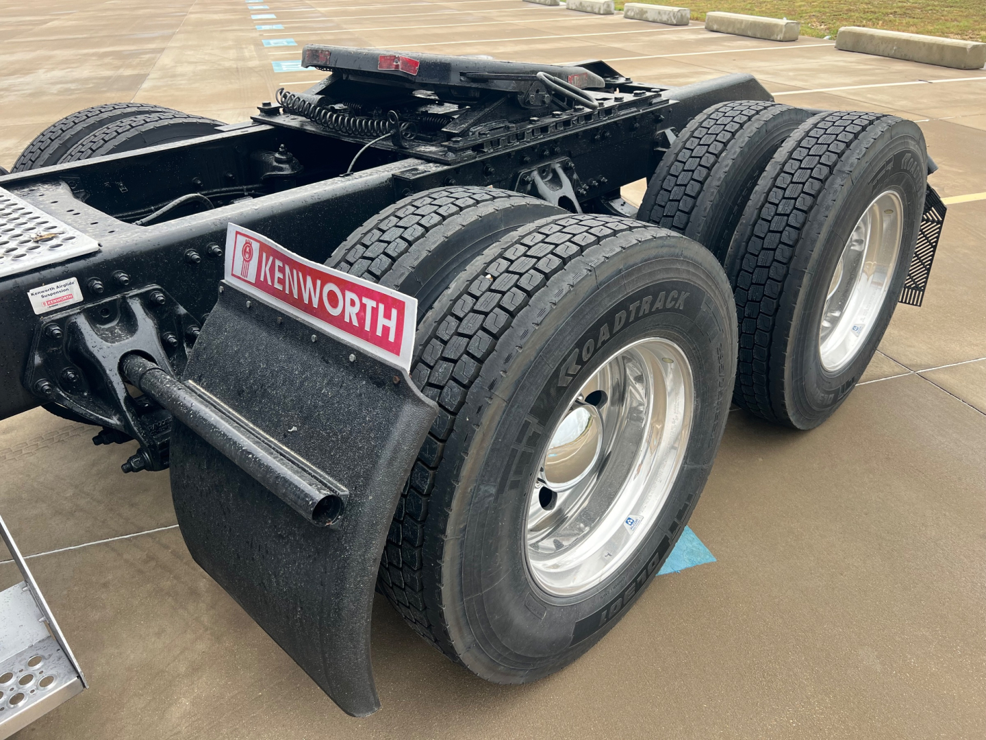Kenworth T680 chassis rear showing dual rear axles with Goodyear Pathmaker tires and Kenworth mud flaps; fifth wheel and frame components visible.