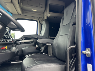 Kenworth T680 cabin interior showing driver seat and dashboard with steering wheel and controls visible.