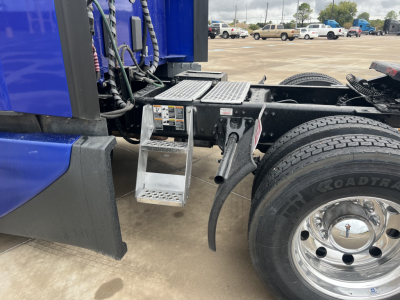 Kenworth T680 truck chassis with steps and fuel/air lines; visible label with VIN and stock number not shown clearly; wheel and tire visible