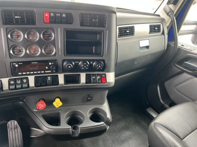 Kenworth T680 dash and driver-side interior showing gauges, controls, and cup holders in a conventional sleeper truck cab.