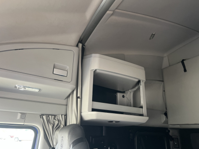 Kenworth T680 interior sleeper cab upper storage cabinet showing open compartment and light grey interior panels.