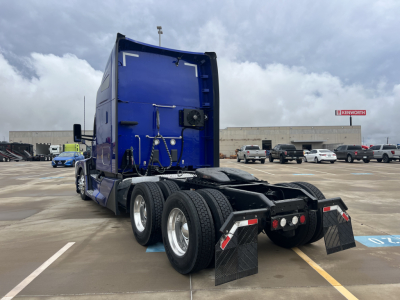 Kenworth T680 tractor, blue sleeper cab, rear view showing dual rear axles and mudflaps.