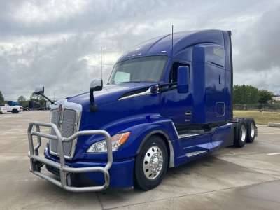 Kenworth T680 conventional sleeper truck in blue, front grille guard, side view showing dual rear axles and chrome wheels.