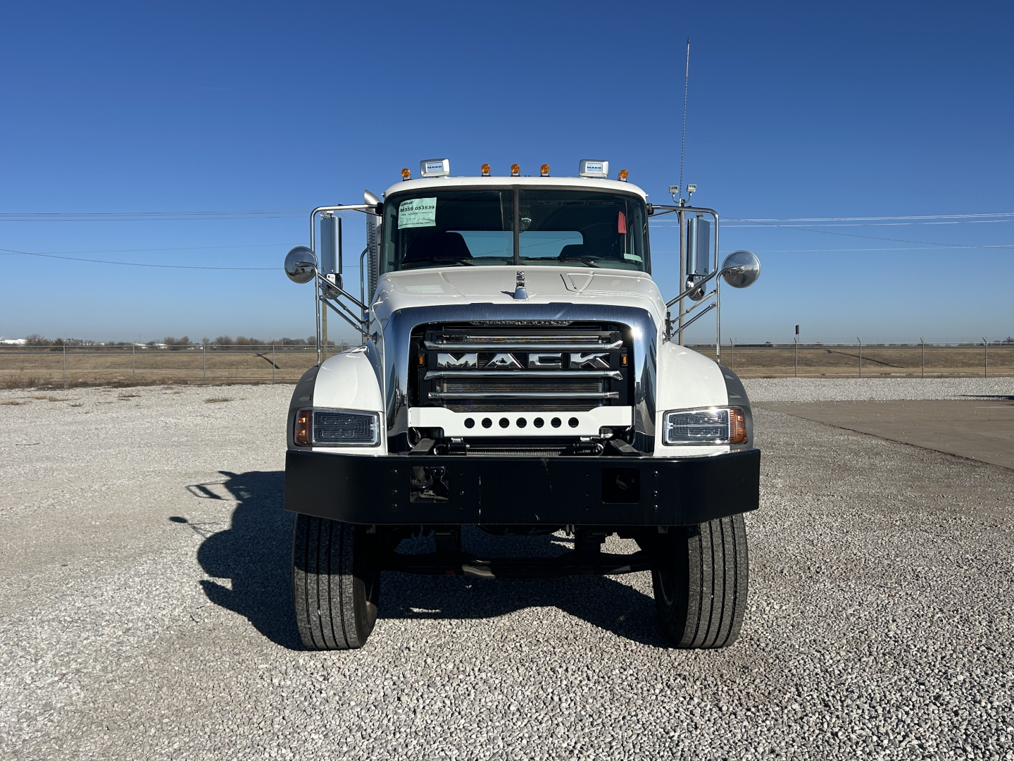 Front view of a new 2026 Mack GR64F Cab and Chassis showing Mack grille, chrome bumper, large dual mirrors, and headlamps.