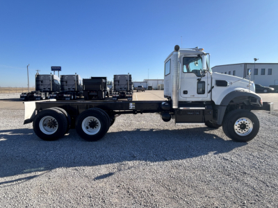 Truck: 2026 Mack GR64F cab and chassis side view showing trailer-height dual rear axles and white cab with black chassis.
