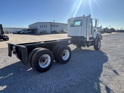 2026 Mack GR64F cab and chassis tractor with dual rear axles and white cab, empty flatbed chassis in a gravel lot.