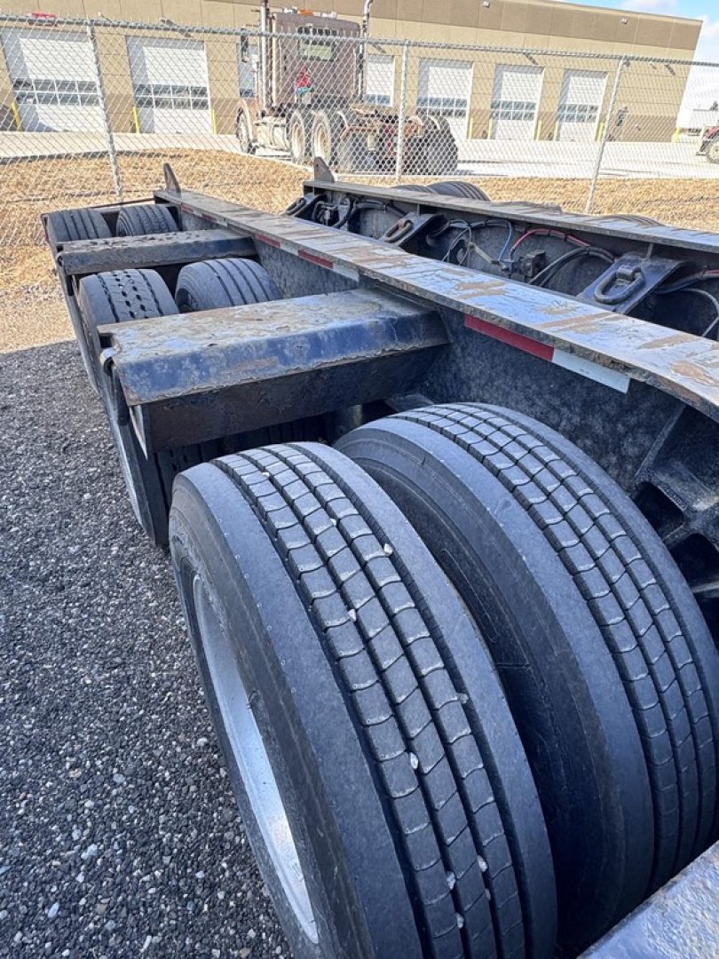 Trailer chassis showing dual rear axles and heavy-duty tires on a Fontaine 55 Lcc lowboy trailer. Visible components include dual rear tires, frame rails, and suspension area.
