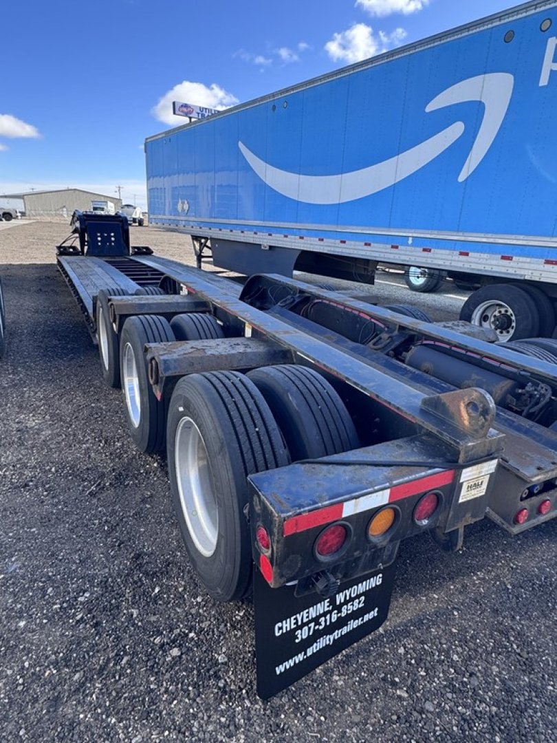 Trailer chassis and wheels of a Fontaine lowboy trailer showing dual tandem axles and rear mudflaps with Cheyenne Wyoming contact