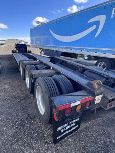 Trailer chassis and wheels of a Fontaine lowboy trailer showing dual tandem axles and rear mudflaps with Cheyenne Wyoming contact