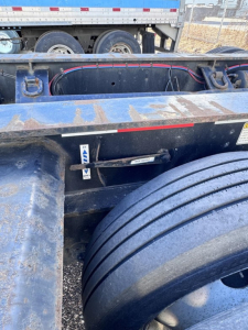 Trailer chassis and wheel area of a Fontaine 55 Lcc lowboy showing frame, axles, and wiring harness.