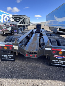 Trailer rear view showing lowboy frame and multiple axles with tires, metal beams, and reflectors; Fontaine equipment brand plates visible.