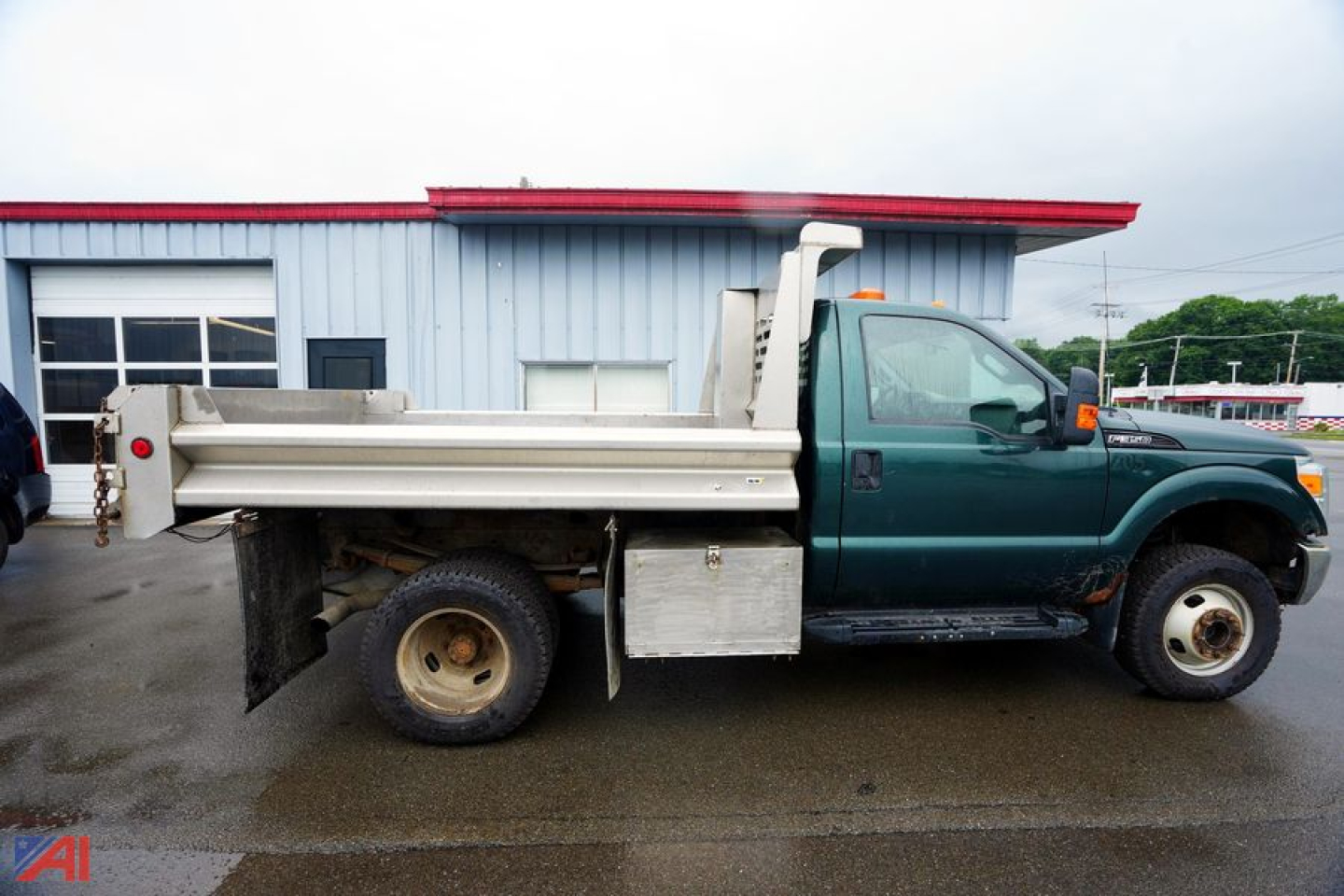 Ford F-350 dump truck side view showing dump bed and hydraulic system with green cab and silver dumping box.