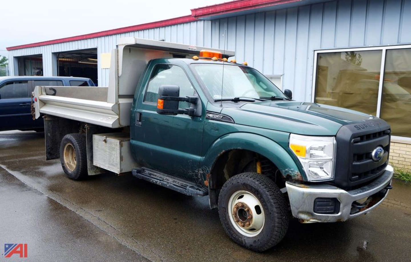Ford F-350 dump truck side view showing dump bed, rear dual wheels, and orange beacon on cab roof.