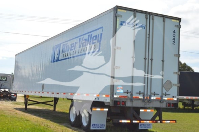 Utility trailer showing River Valley Trailers lettering and graphics on side, with rear doors and triple-axle configuration.