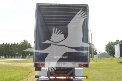 Trailer rear view showing a graphic white bird decal on dark back doors, red taillights, and black bumper with reflective tape.