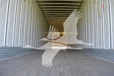Interior of a utility trailer with metal walls and wooden floor showing a long rectangular cargo space.