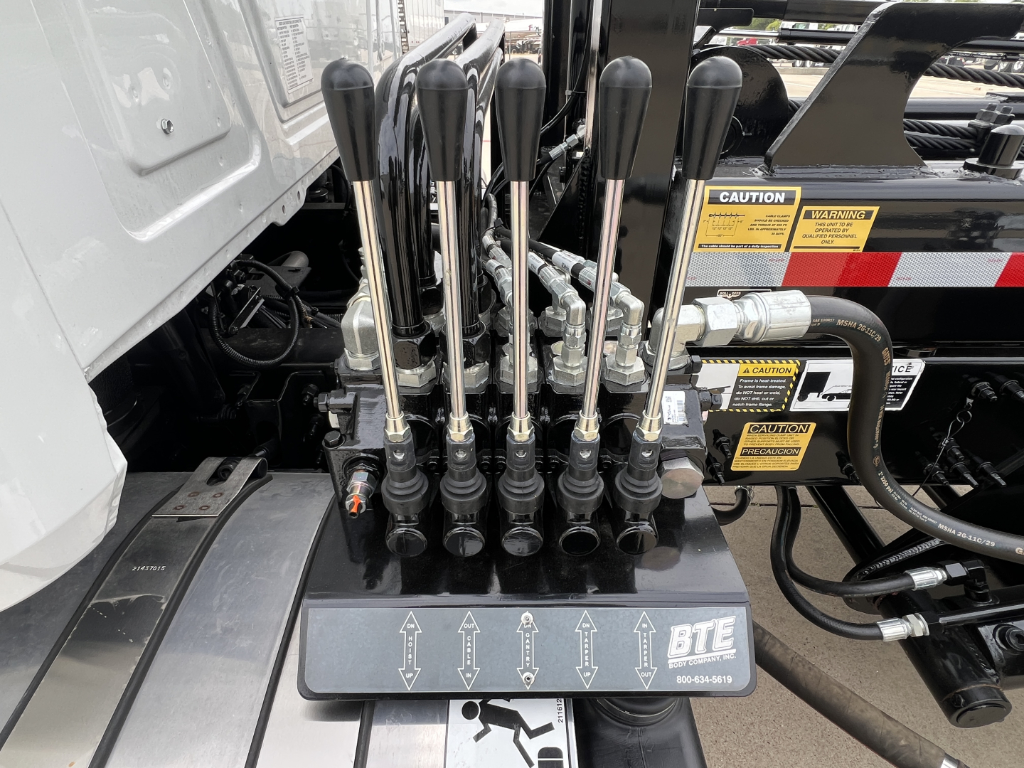 Control levers on Mack GR64B rolloff truck with multiple joystick levers and BTE control module in cab area.