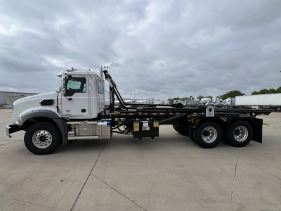 Mack GR64B heavy-duty roll-off truck side view showing chassis and hydraulic hooklift system.
