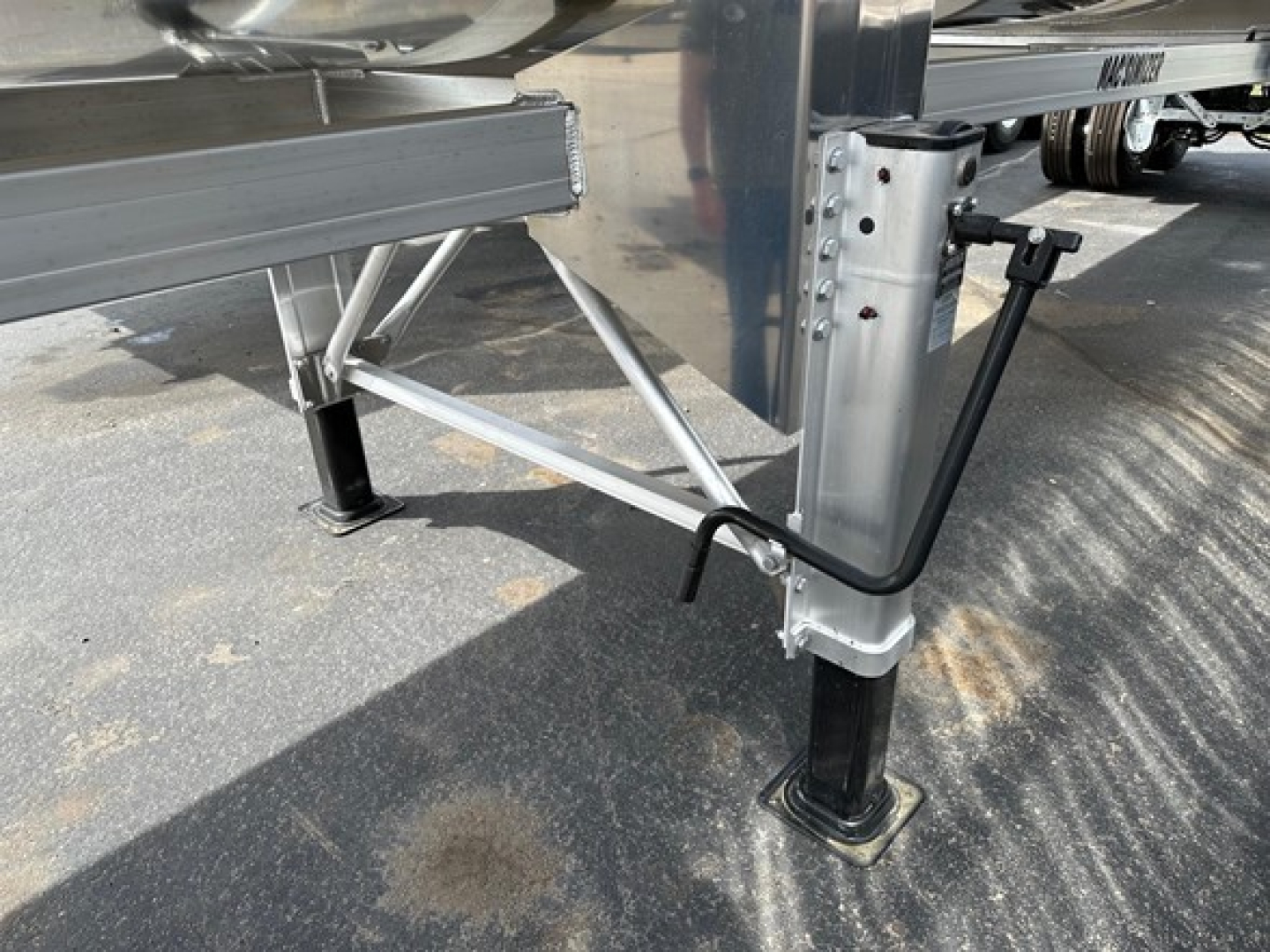 Trailer landing gear and frame of a Mac Macsimiser dump trailer showing adjustable leg and support brace with steel frame and black foot pads.