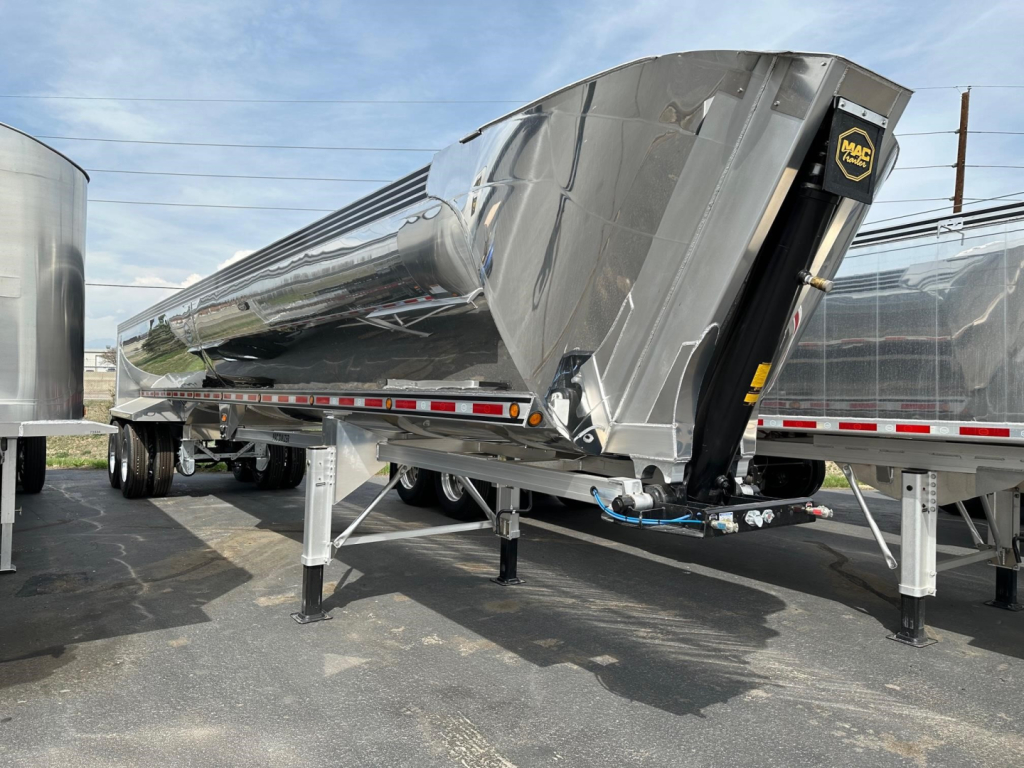 Mac Macsimiser dump trailer side view showing polished steel hopper and hitch mechanism with supports and landing legs.
