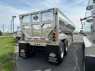 Dump trailer rear view showing MAC aluminum body, dual axle with mud flaps and taillights, chrome frame, and rear gate.