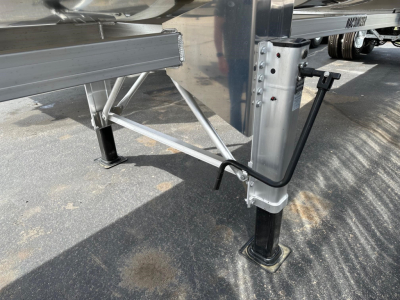 Trailer landing gear and support legs with structural framing and pin connections visible; no legible model text or markings in the image.