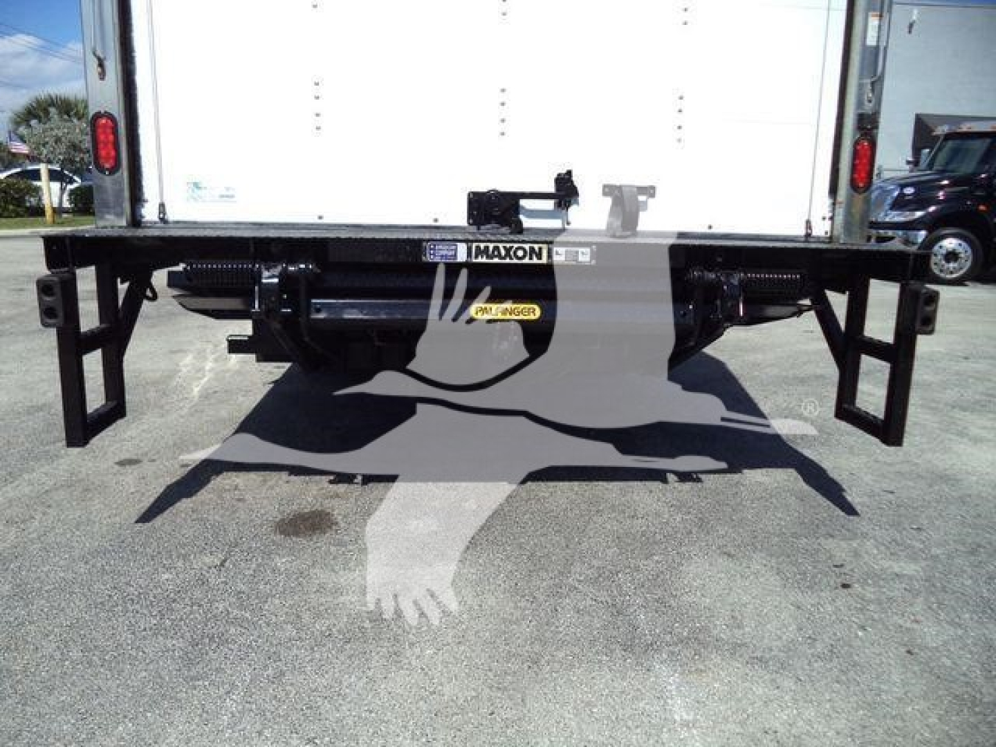 Isuzu NPR HD rear view showing Maxon bumper and undercarriage with plate and storage, cargo box tailgate visible.