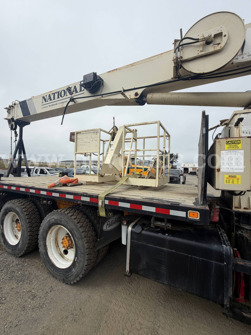 Peterbilt 357 utility flatbed with crane; side view showing National crane arm, dual rear axles, and platform with warning labels.
