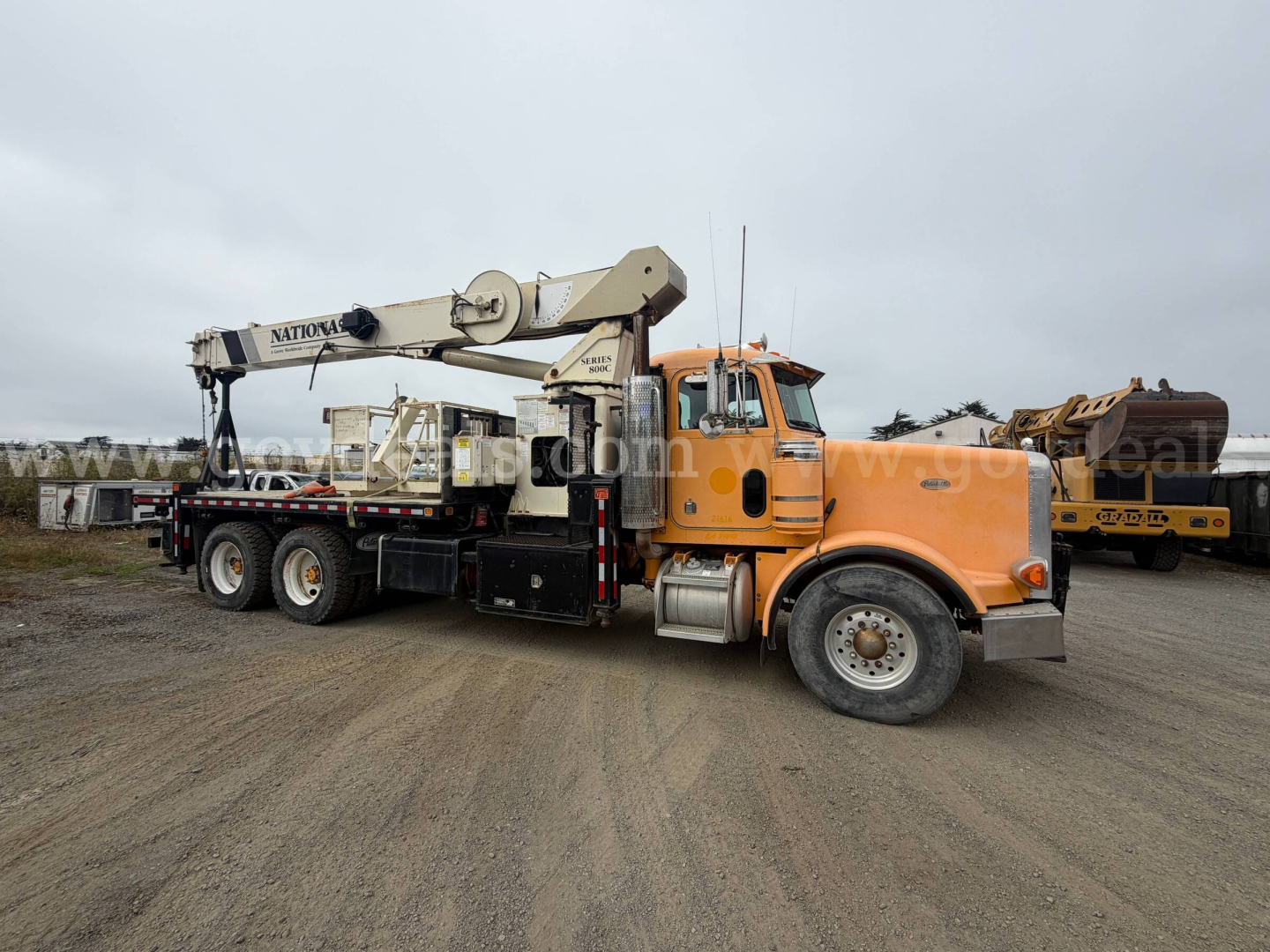 Peterbilt 357 tow truck with large crane arm in orange cab and gray boom, side view