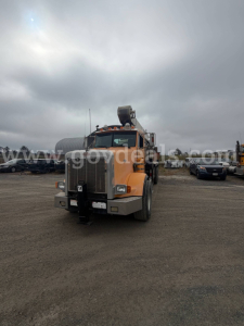Peterbilt 357 truck in a dirt lot, orange cab, front view with chrome grille and bumper, visor lights, and sleeper cab.