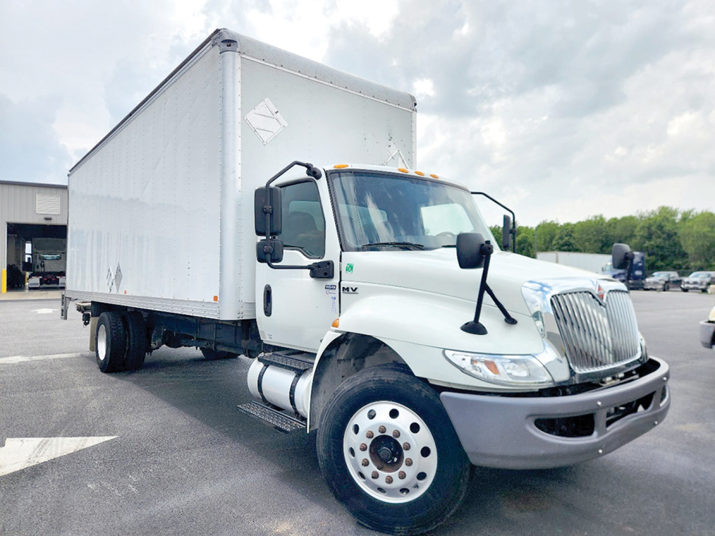 Truck engine bay and cab of a white 2021 International 4300 conventional daycab front-left view.