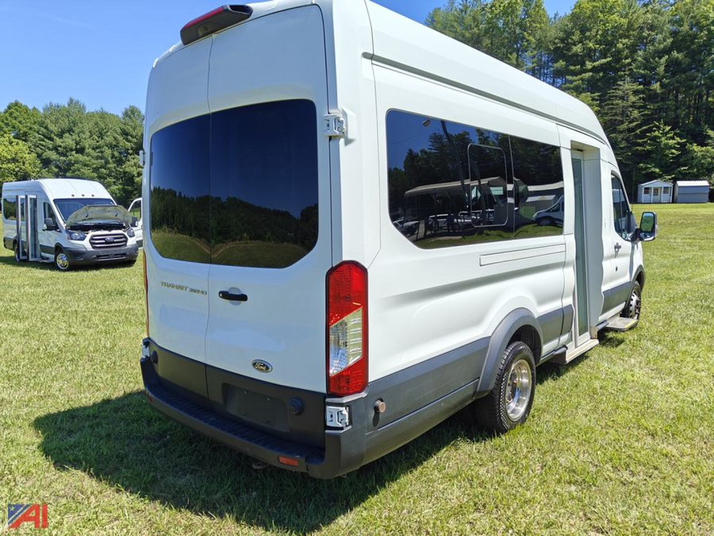 Ford Transit van rear-right view showing wheelchair lift with side window, white body, black bumper, and rear doors.