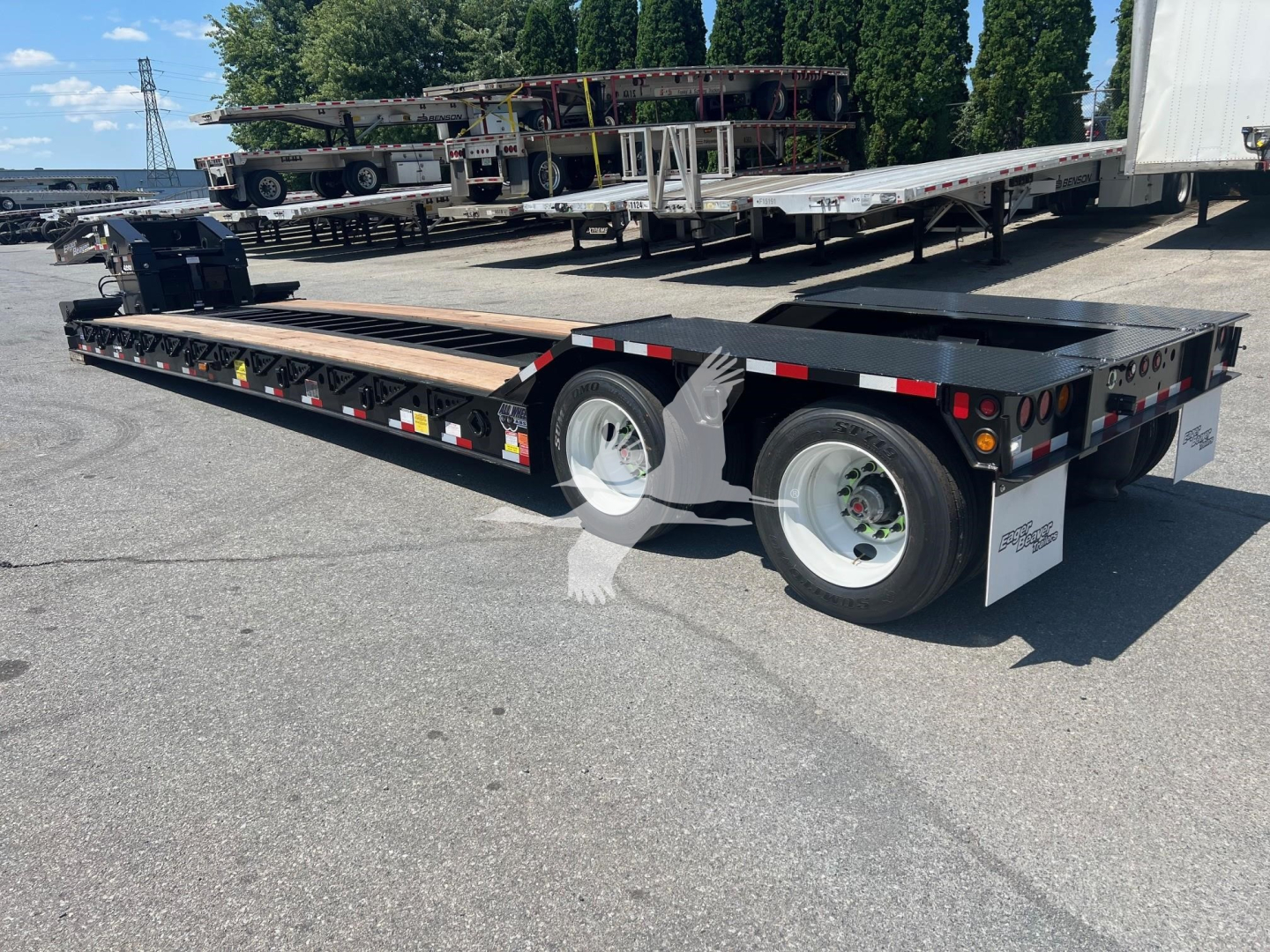 Trailer: lowboy trailer with dual rear axles and long flatbed, black with white wheels, side reflectors, and rear underride protection; shows VL088762 stock tag and VIN plate.