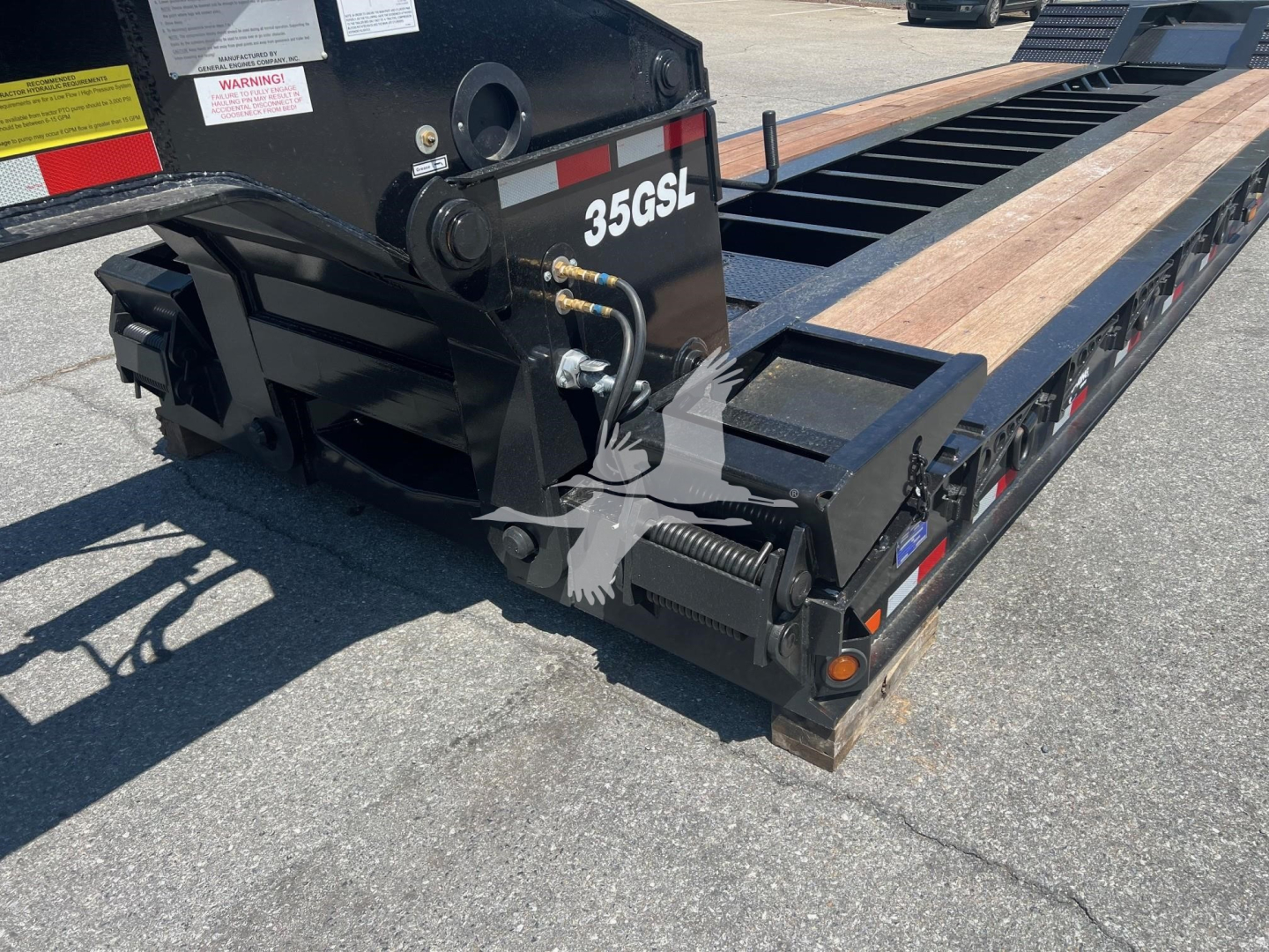 Back end of a lowboy trailer with hydraulic components and the numbers 35GSL on the frame.
