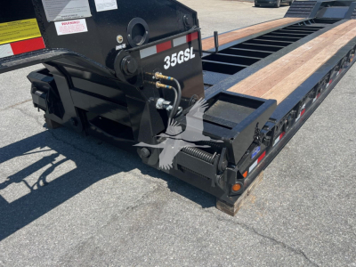 Back end of a lowboy trailer with hydraulic components and the numbers 35GSL on the frame.