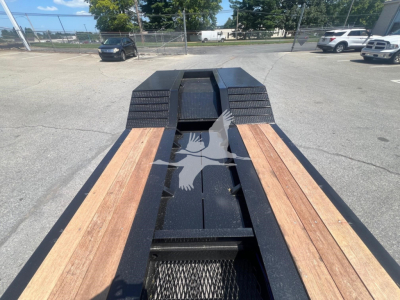 Trailer deck of a lowboy with wooden planks and black steel frame seen from rear, with rubber fenders and metal rails; no readable text visible.