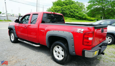 Red 2011 Chevrolet Silverado Z71 4x4 extended cab pickup truck, rear three-quarter view with pickup bed and chrome bumper.