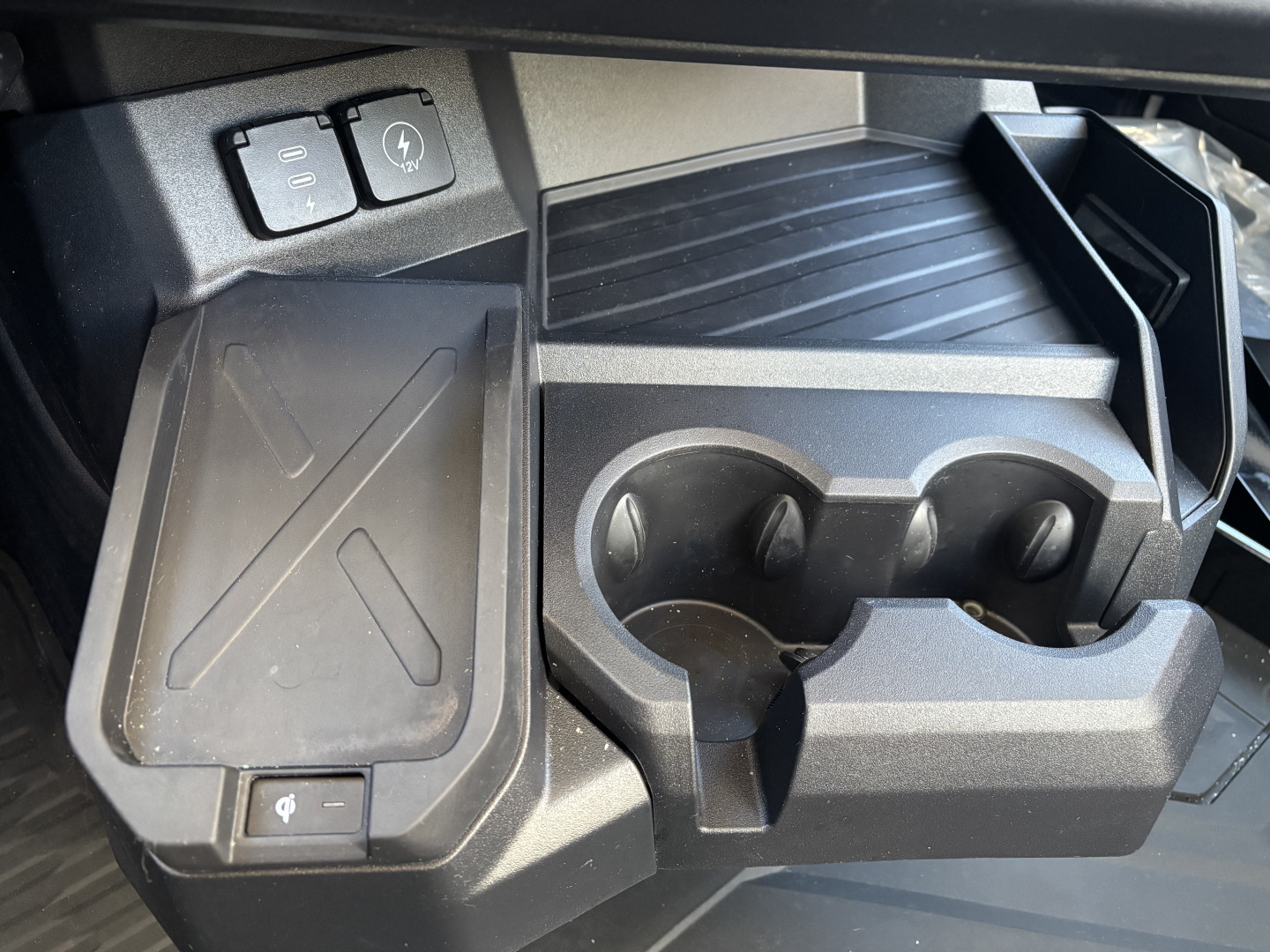 Dashboard area showing cup holder and power port on Mack PR64T interior, with rubber mat and front storage compartment.