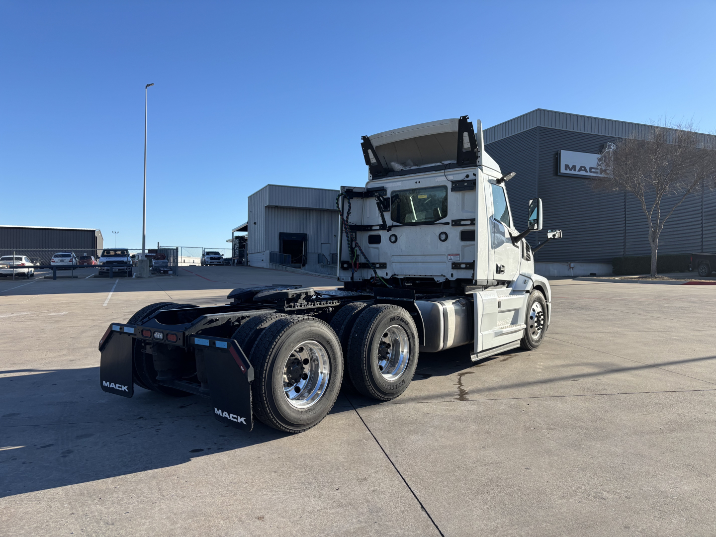 Semi truck tractor rear three-quarter view showing Mack PR64T cab and dual rear axles in a dealership lot.