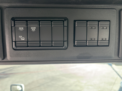 Dashboard switch panel showing rocker switches with door light and window controls in a Mack PR64T cab panel