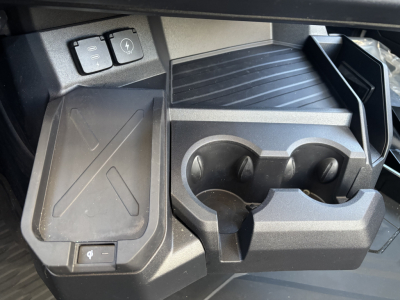 Dashboard area showing cup holder and power port on Mack PR64T interior, with rubber mat and front storage compartment.