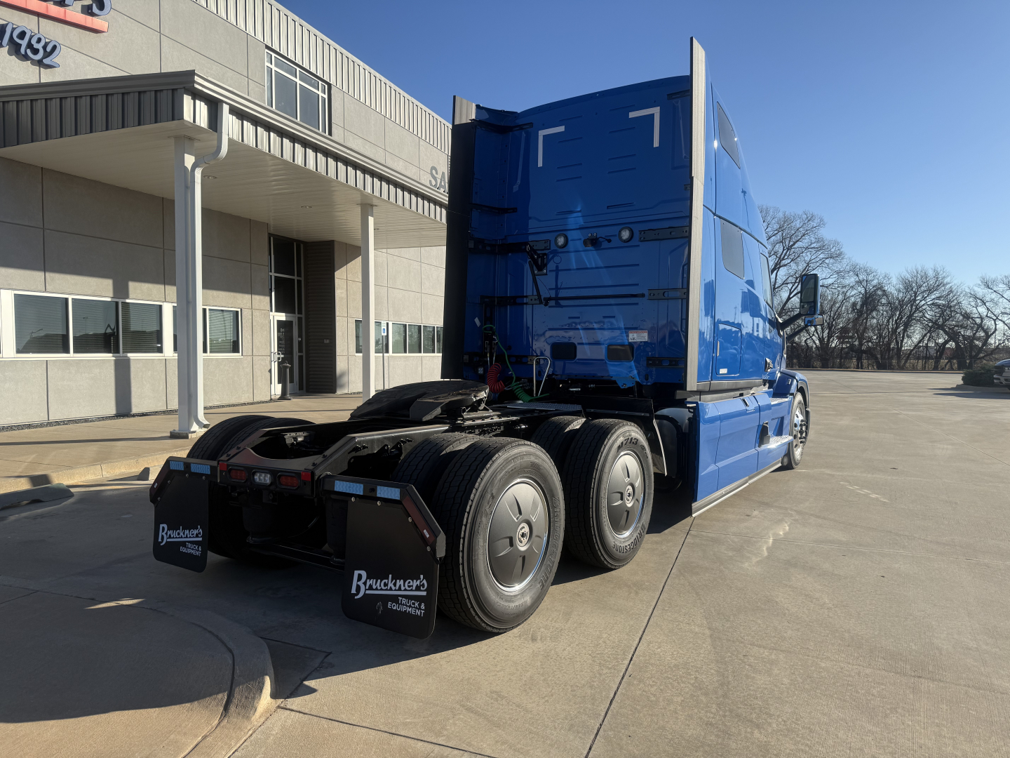 Blue 2026 Mack PR64T76H tractor truck rear three-quarter view showing sleeper cab and tandem axles.