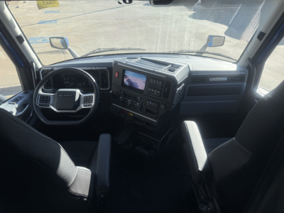 Dashboard and steering wheel area of a Mack truck cab interior with center console and digital screen visible.