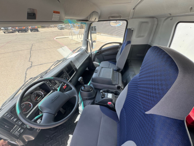 Isuzu FTR truck cab interior showing steering wheel, dashboard, and blue fabric seats.