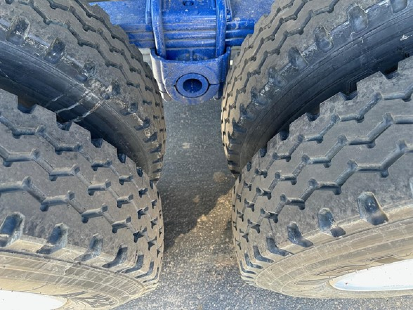 Trailer dual-tire axle close-up showing rugged tread tires and blue frame central linkage for Ranco Ed26-34 trailer.