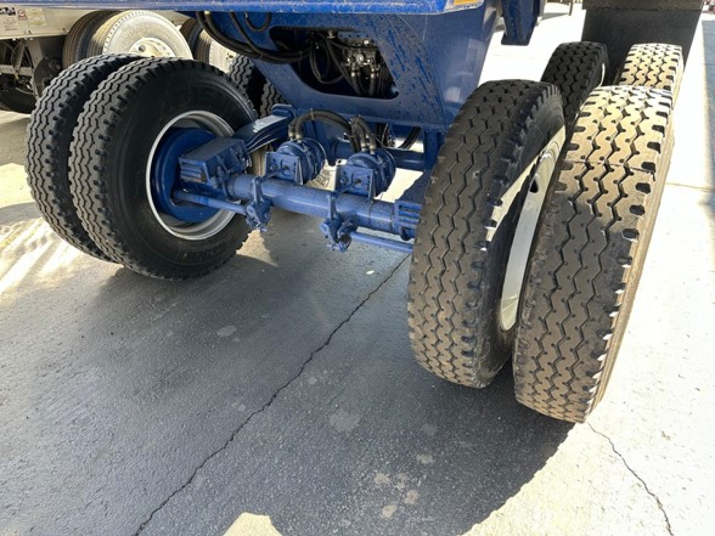 Ranco Ed26-34 trailer undercarriage showing dual rear axles with large off-road tires and blue-painted suspension components.
