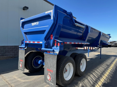 Ranco ED26-34 dump trailer in blue, side and rear view showing dual rear tires, mud flaps, and RANCO branding on tailgate.